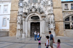Parents discussing outside a church as a girl performs acrobatic feats nearby